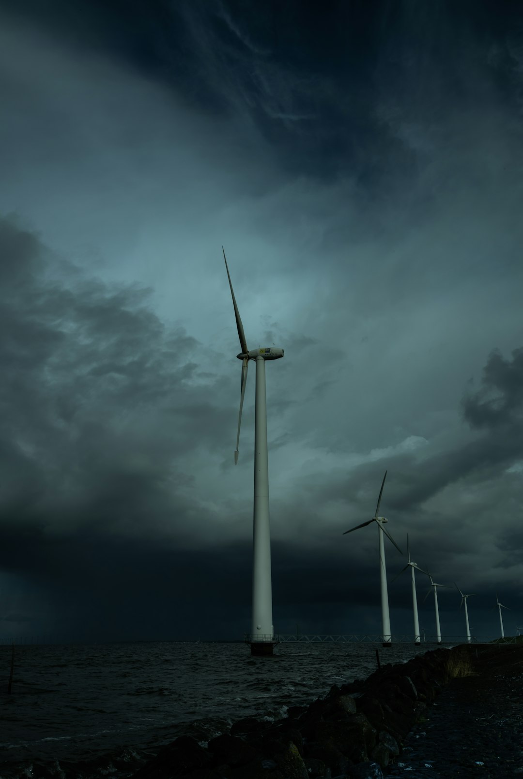 white wind turbine under gray clouds