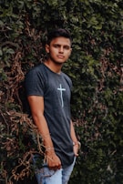 A young man leaning against a wall, showcasing klyra’s bold graphic tee.