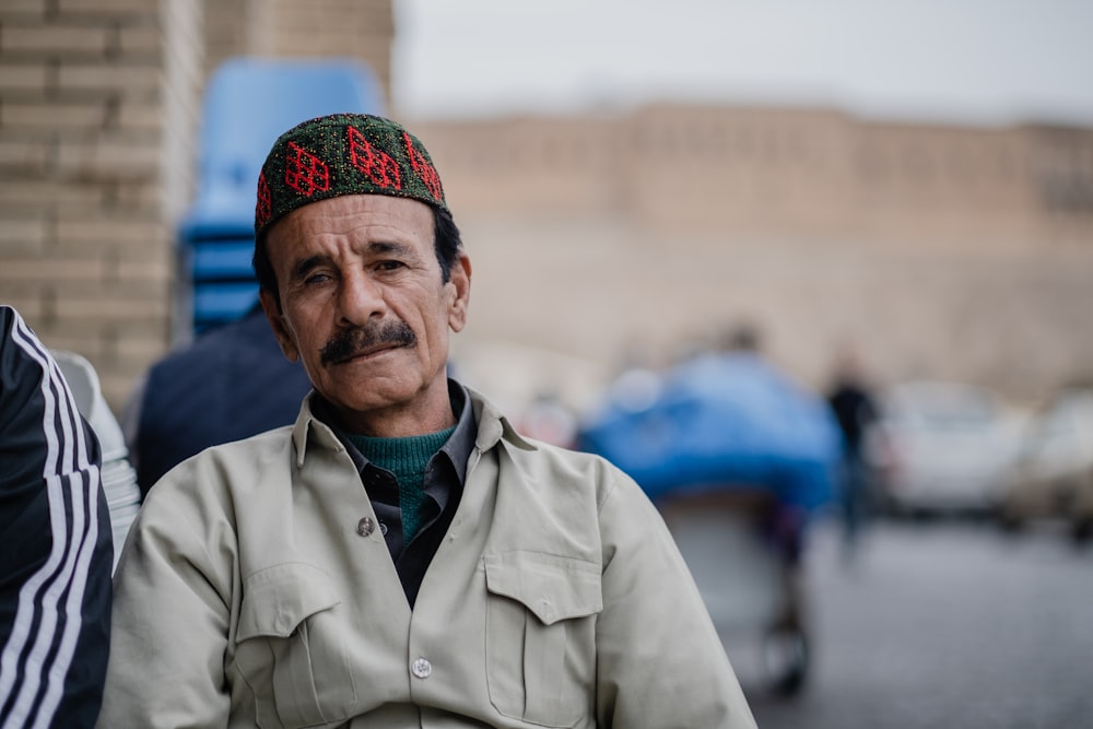 homme en chemise boutonnée grise portant une casquette en tricot bleu et rouge