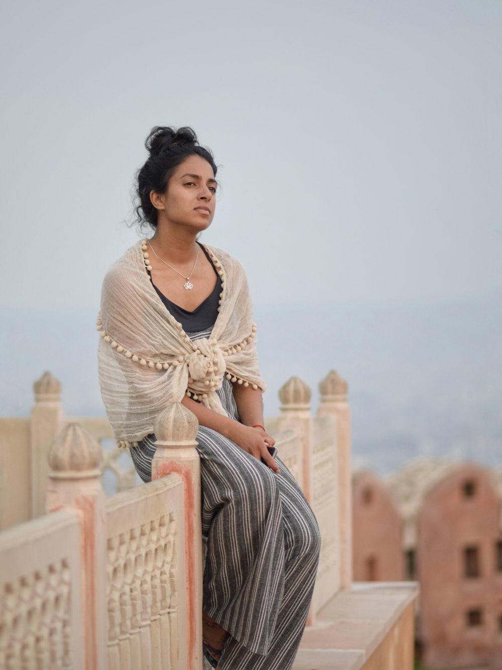 woman in white lace long sleeve shirt and gray and white striped pants sitting on white