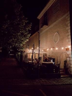 Outdoor seating area with customers enjoying meals under string lights in the evening