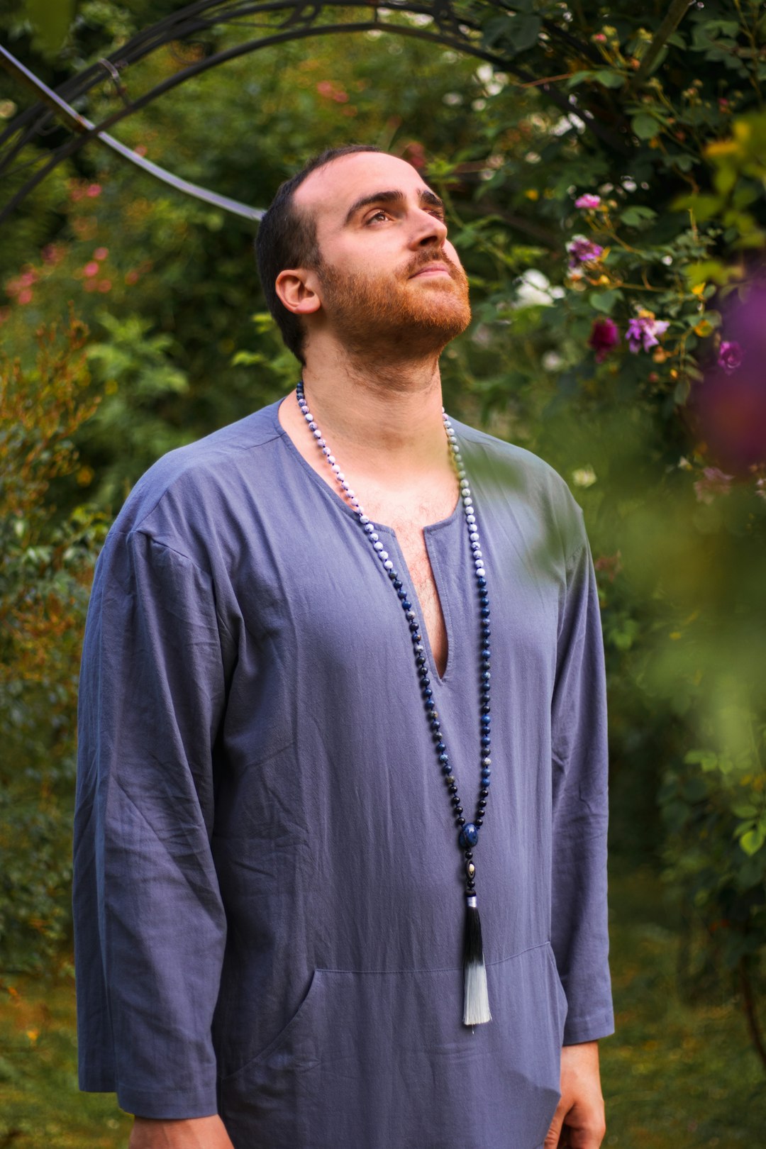 man in blue long sleeve shirt standing near pink flowers during daytime