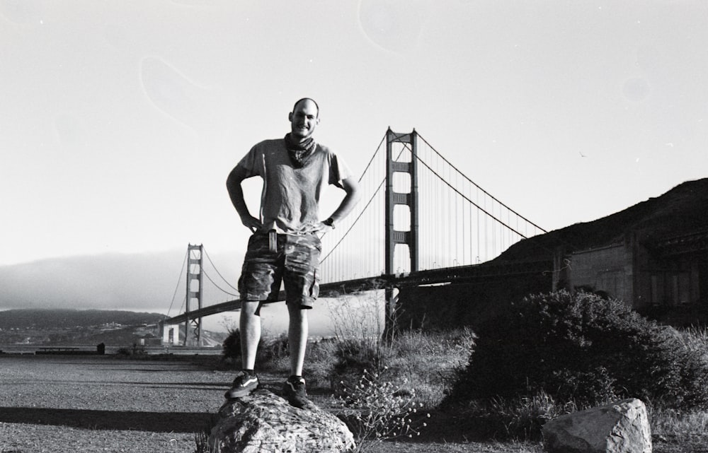 man in black t-shirt and gray shorts standing on rock