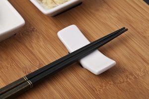Elegant wooden chopsticks resting on a minimalist white plate.