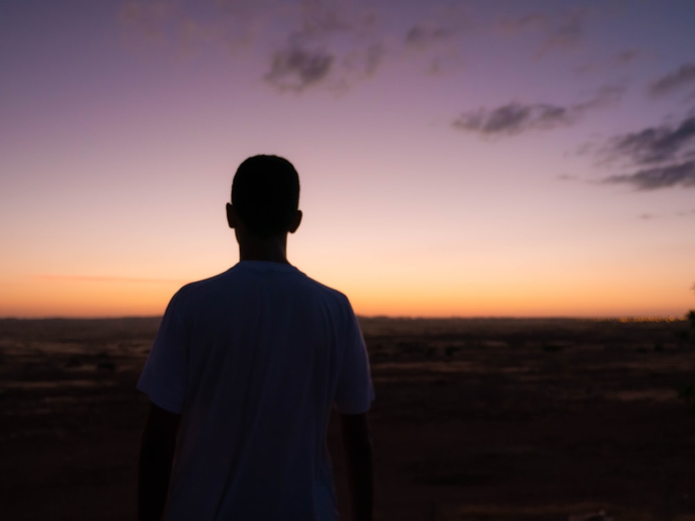 man in white shirt standing on field during sunset