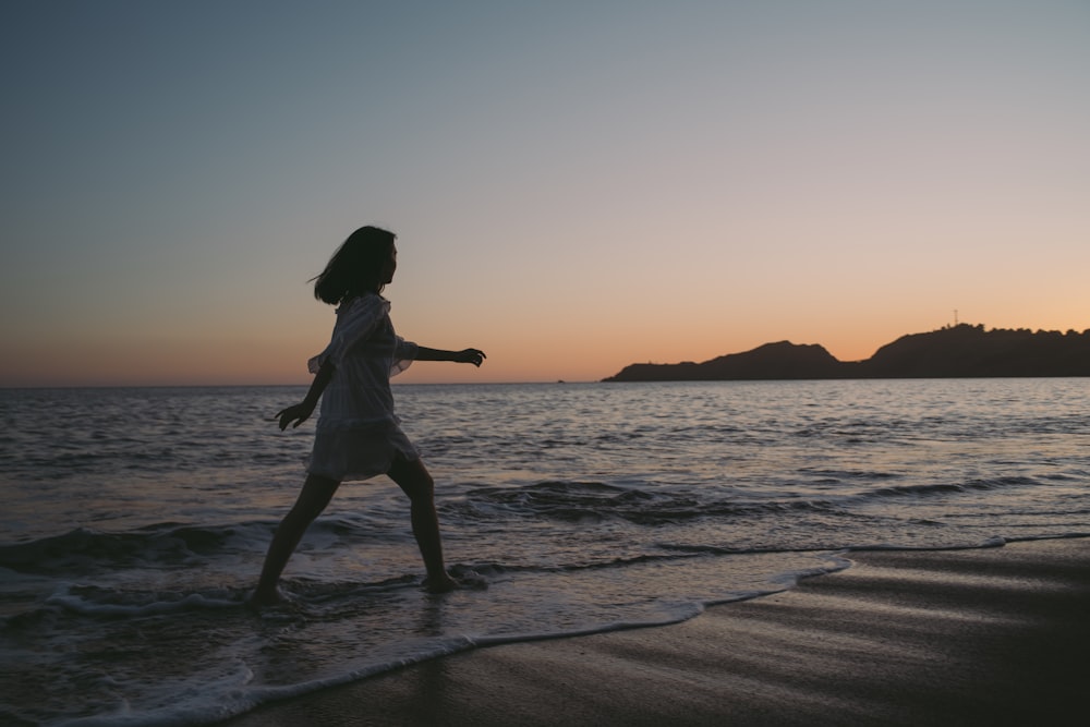 silhouette of woman running on beach during sunset