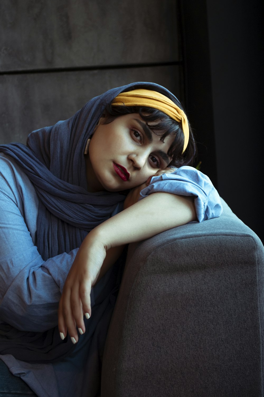 Frau im blauen Hijab sitzt auf schwarzer Couch
