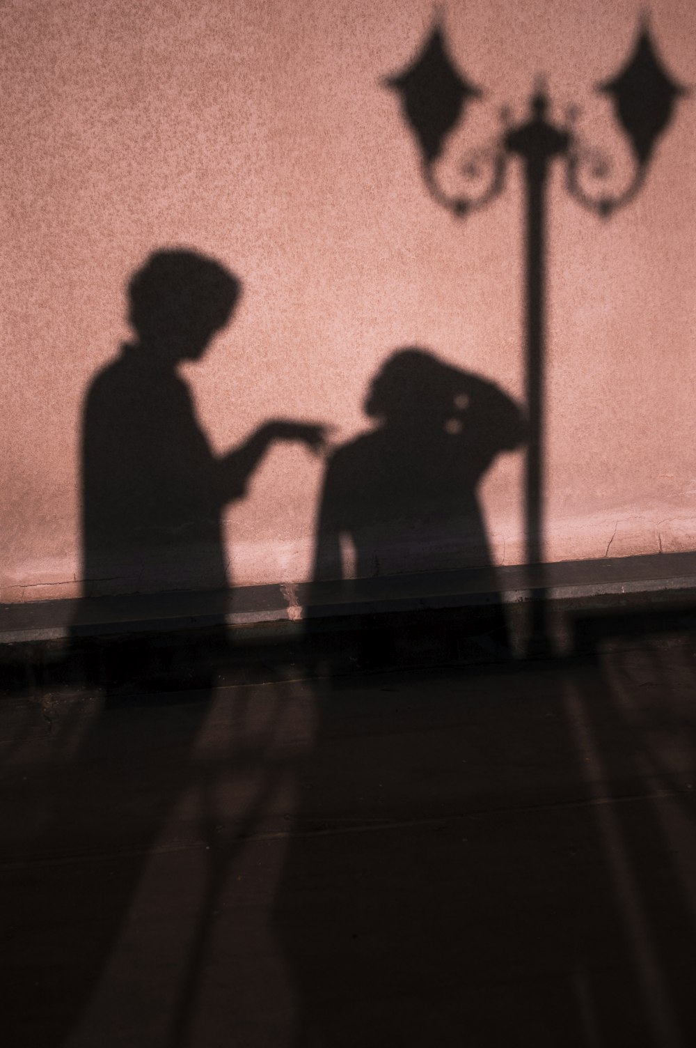 silhouette of 2 person standing beside orange wall