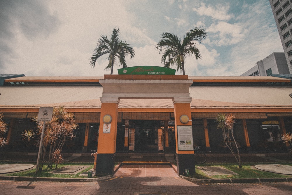 brown and green concrete building near palm trees during daytime