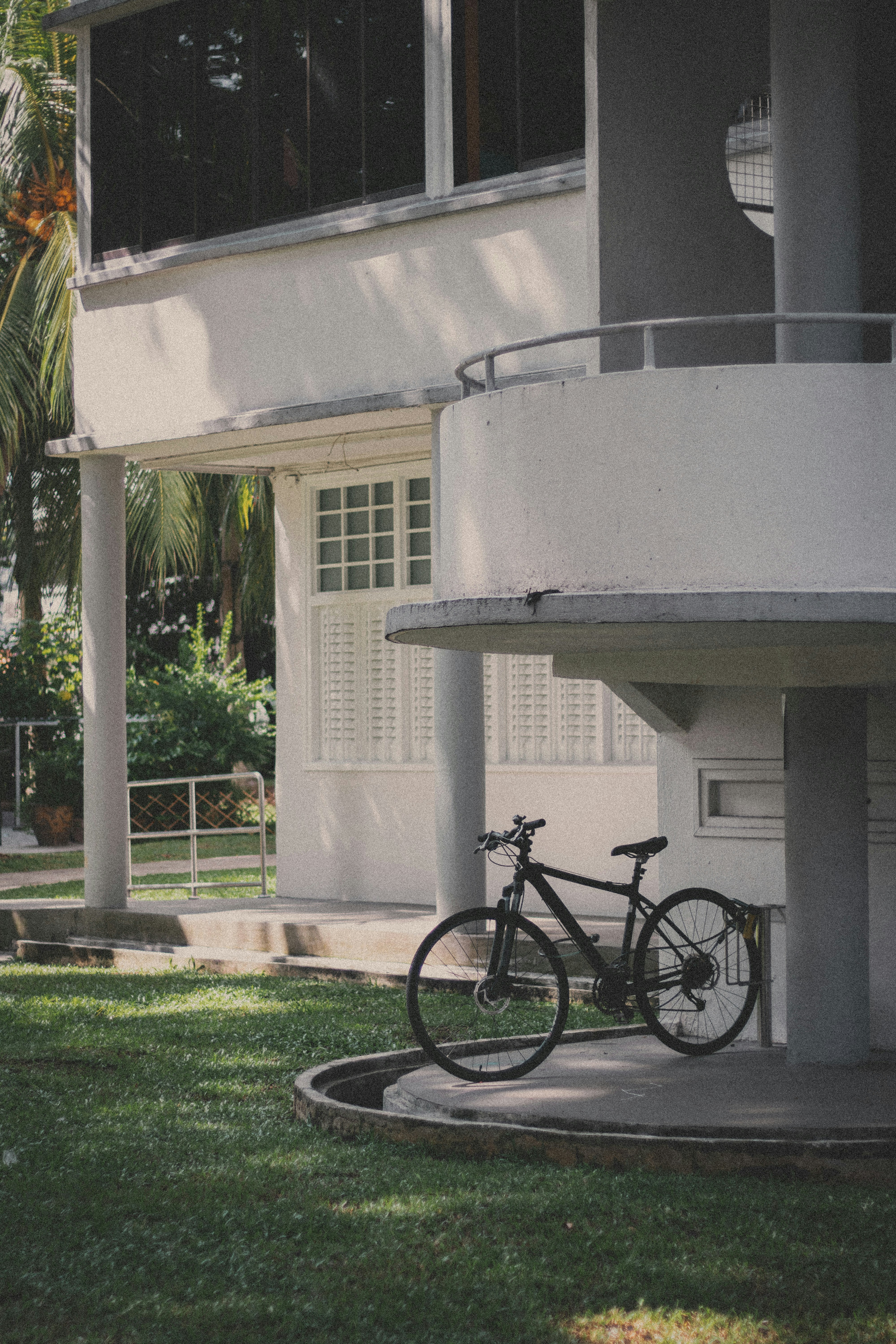 black bicycle parked beside white concrete building during daytime