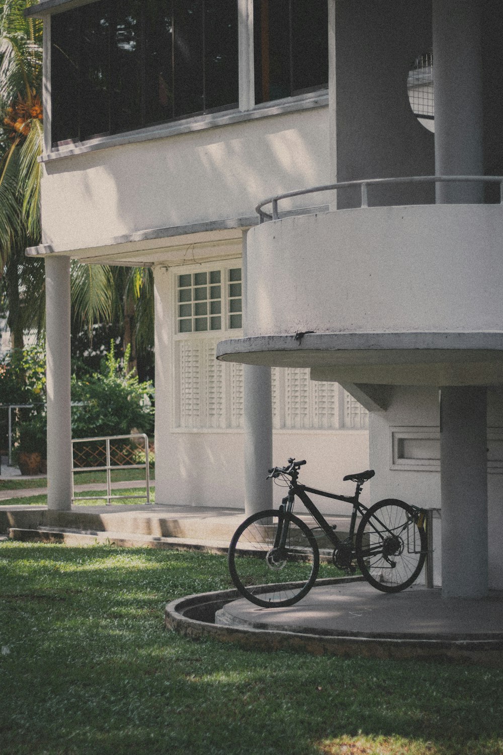 Bicicleta negra estacionada al lado de un edificio de hormigón blanco durante el día