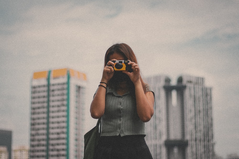 woman in gray shirt holding black camera