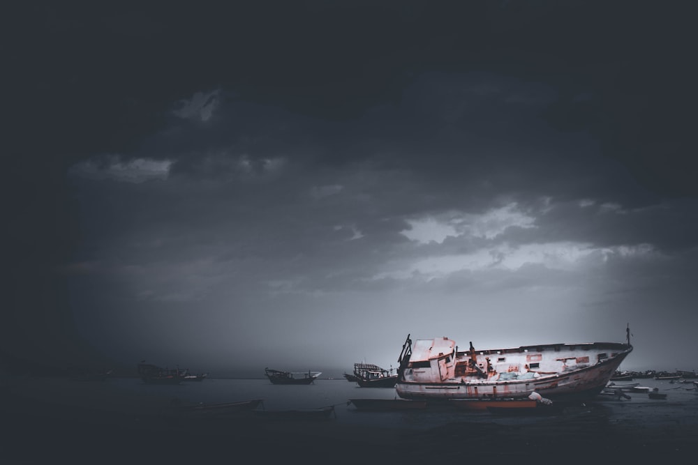 red and white boat on sea under gray clouds