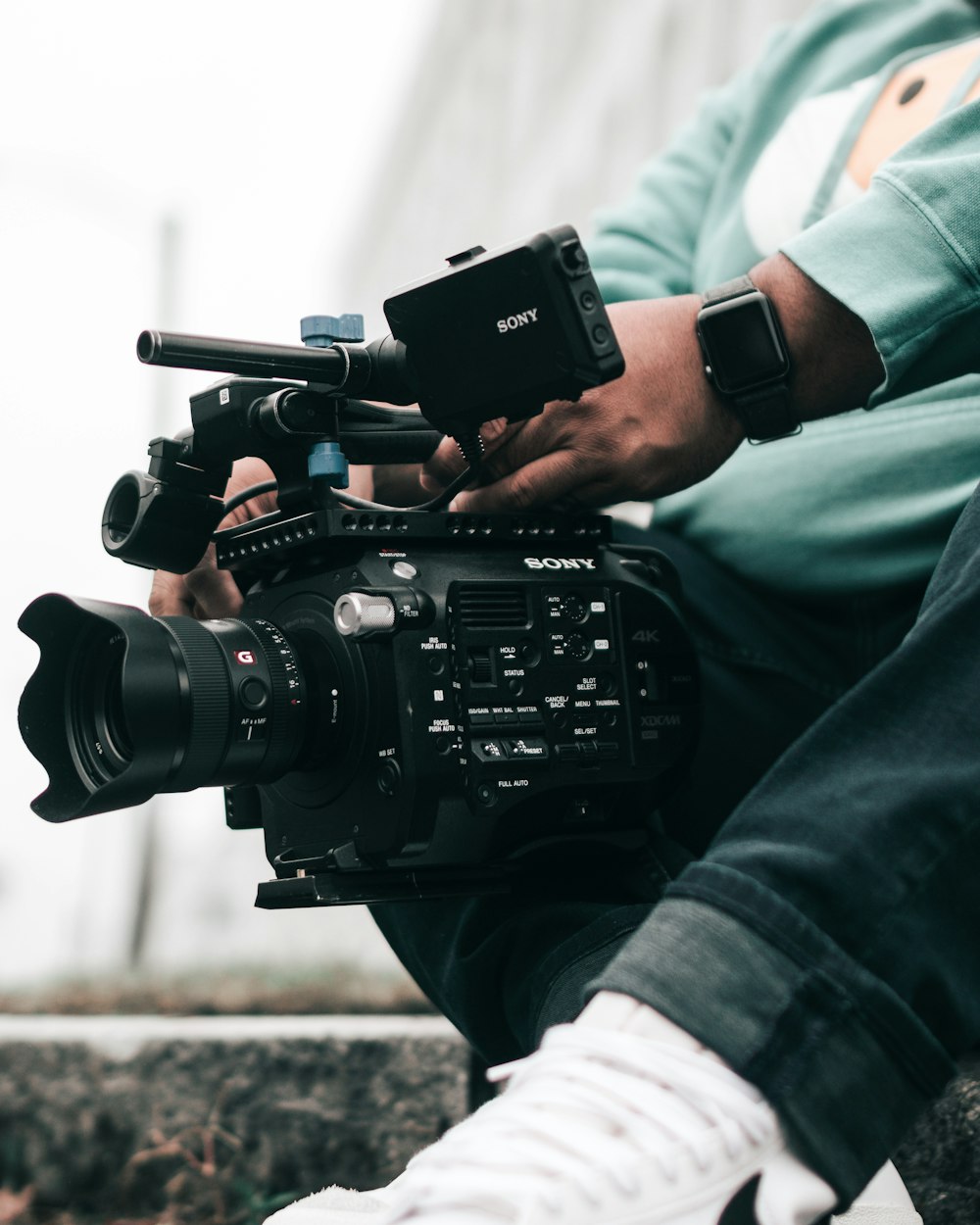 person in green jacket holding black dslr camera