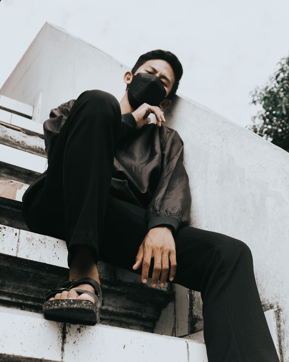 man in black coat and black pants sitting on concrete bench