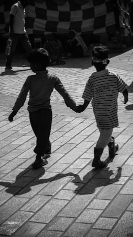 boy in black and white striped long sleeve shirt walking on sidewalk during daytime