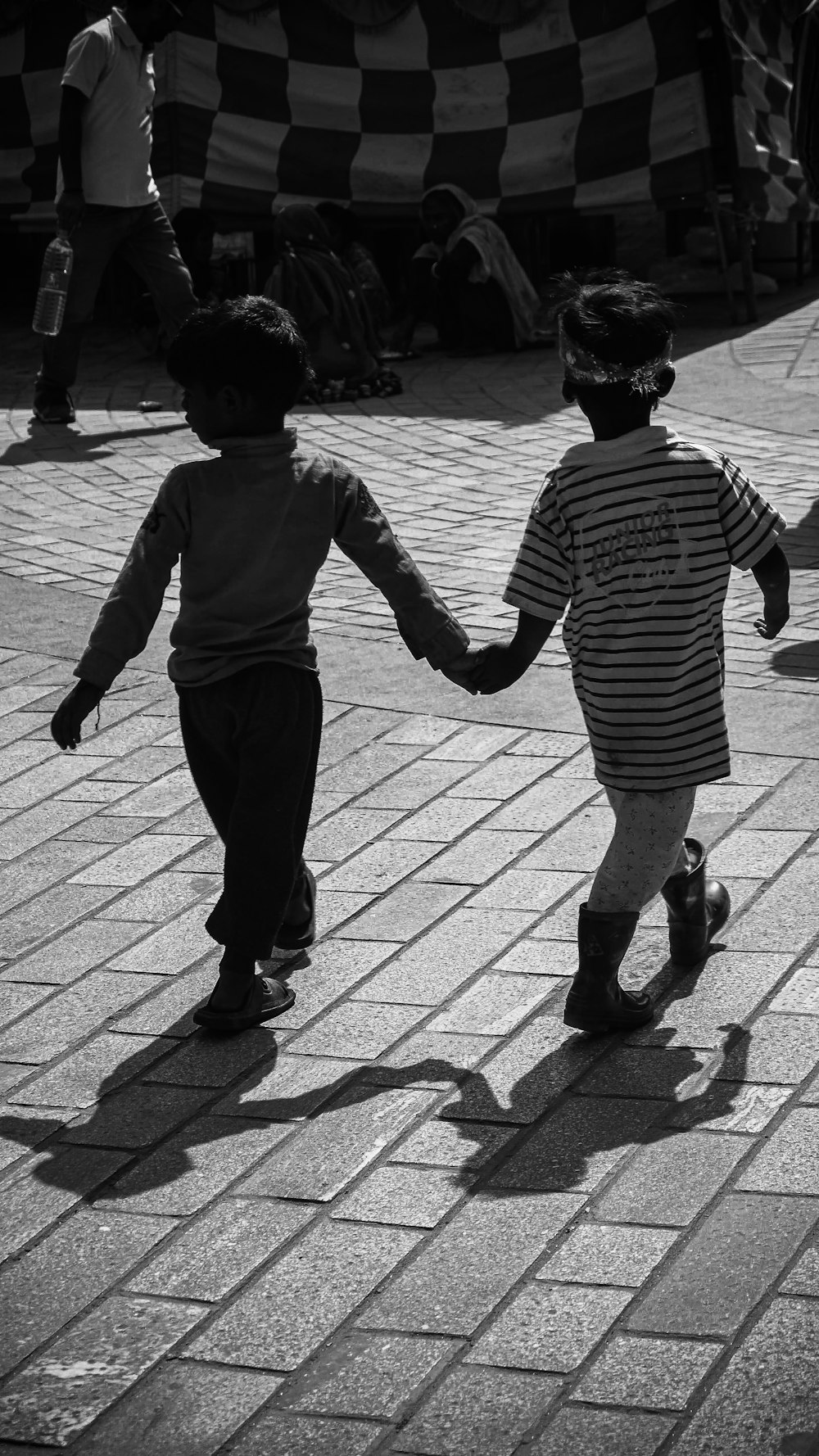menino em preto e branco listrado camisa de manga comprida andando na calçada durante o dia