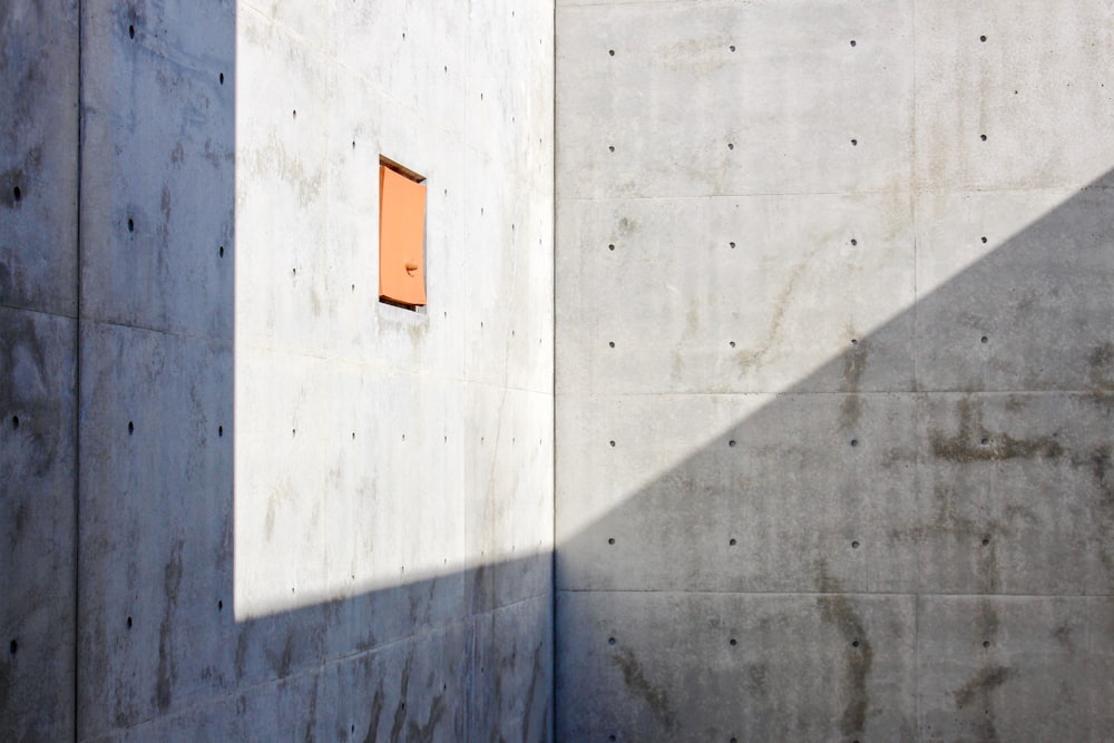 Panneau orange et blanc sur un mur en béton gris