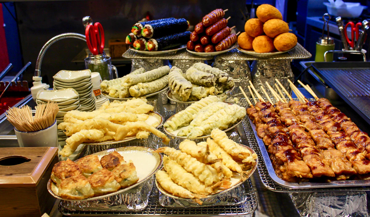 A street food stall spread of Korean skewers, tempura and pajeon