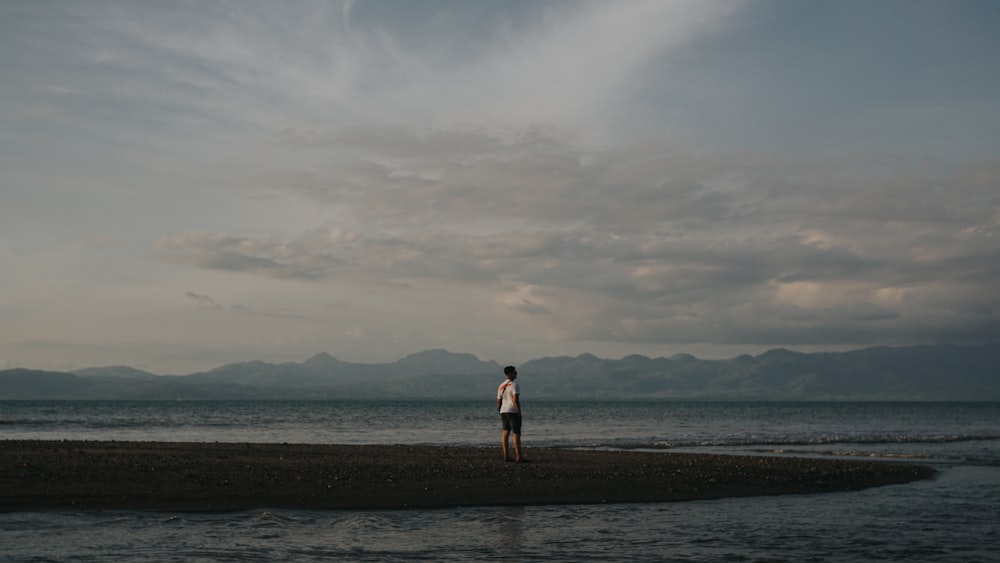 2 women standing on brown sand near body of water during daytime