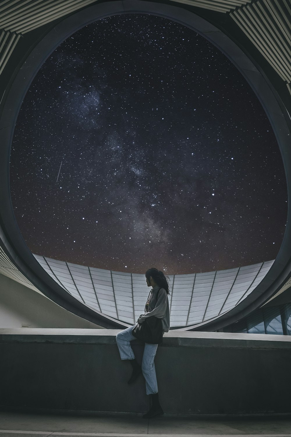 man in black jacket and black pants standing on white building during nighttime