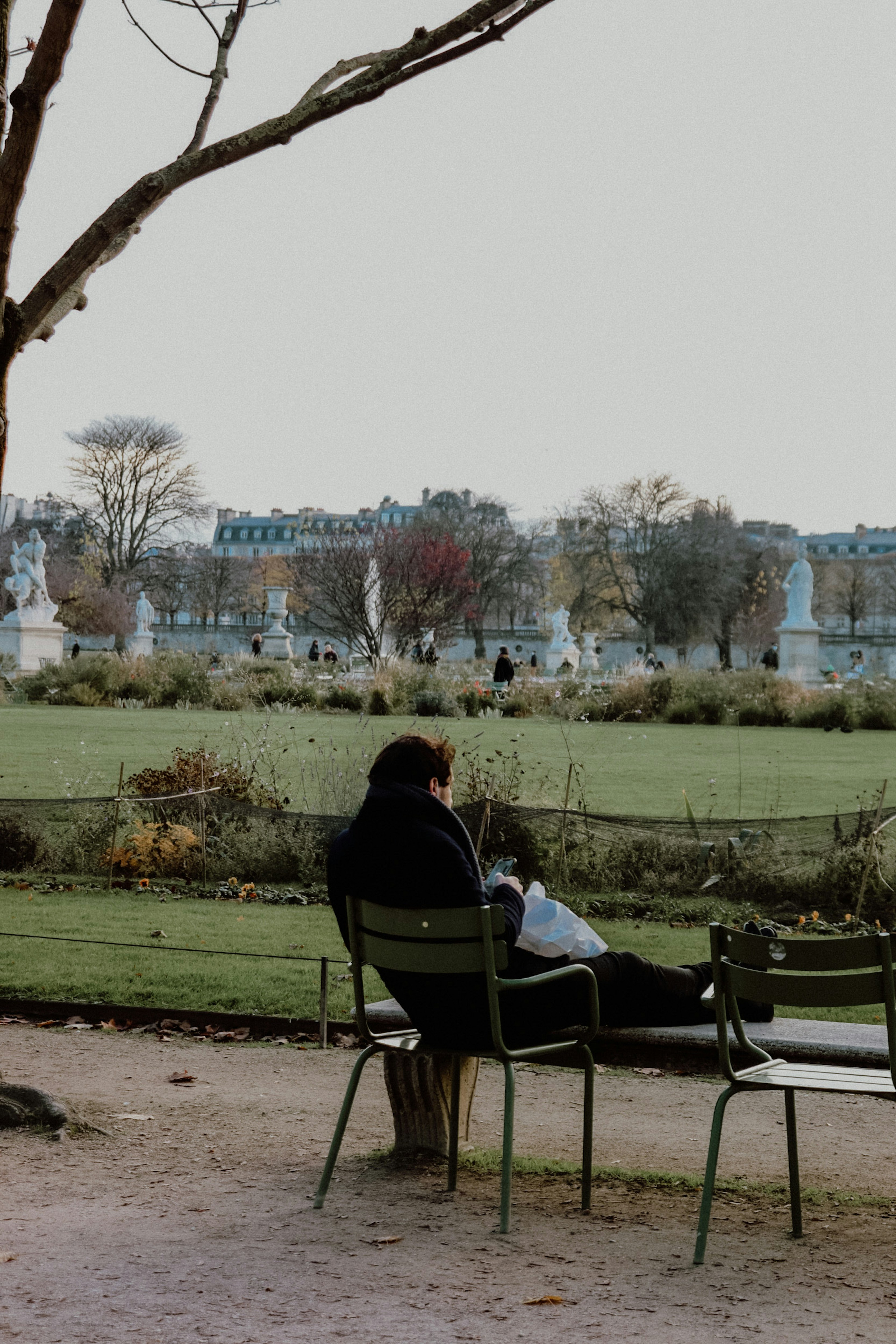 man in black jacket sitting on black metal bench during daytime