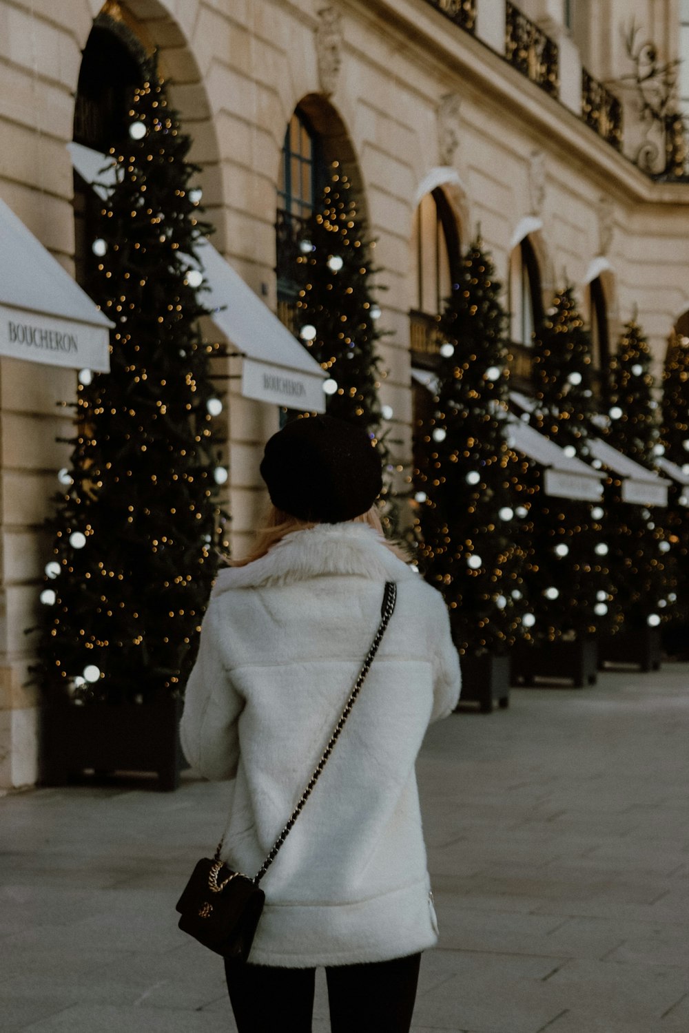 person in white coat standing near christmas tree