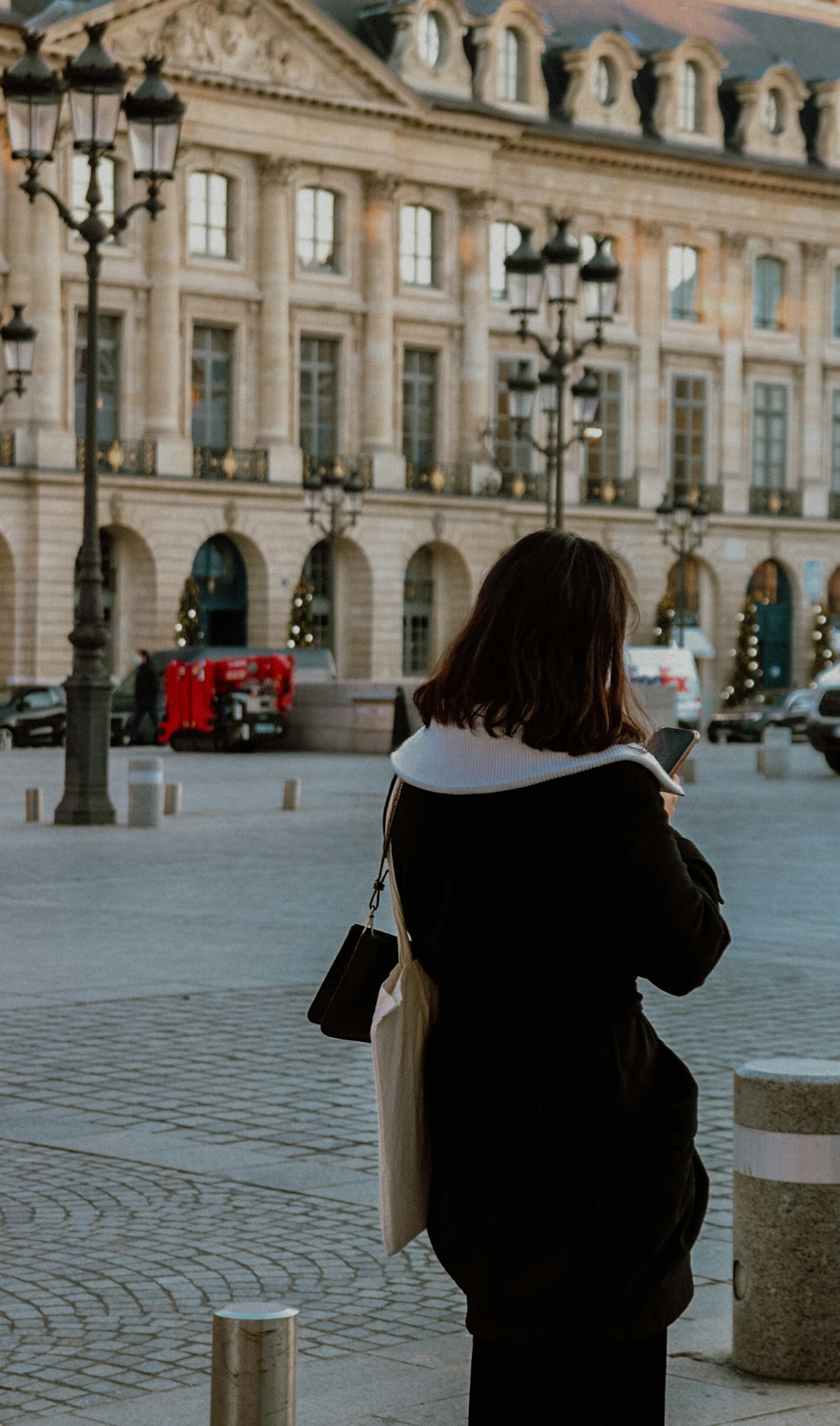 woman in black coat standing on sidewalk during daytime