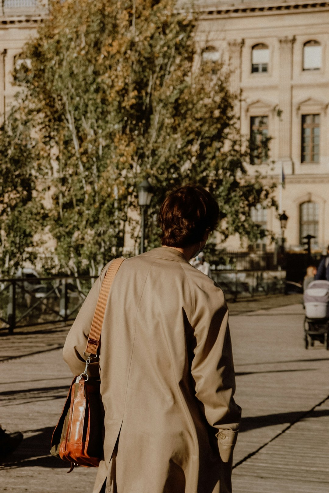 woman in beige long sleeve shirt walking on sidewalk during daytime