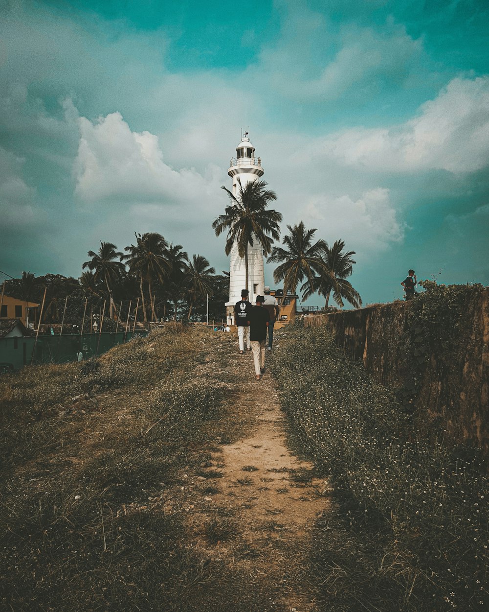 people walking on pathway under cloudy sky during daytime