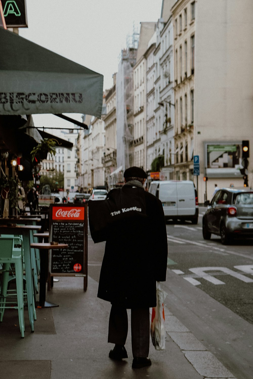 man in black coat standing on sidewalk during daytime