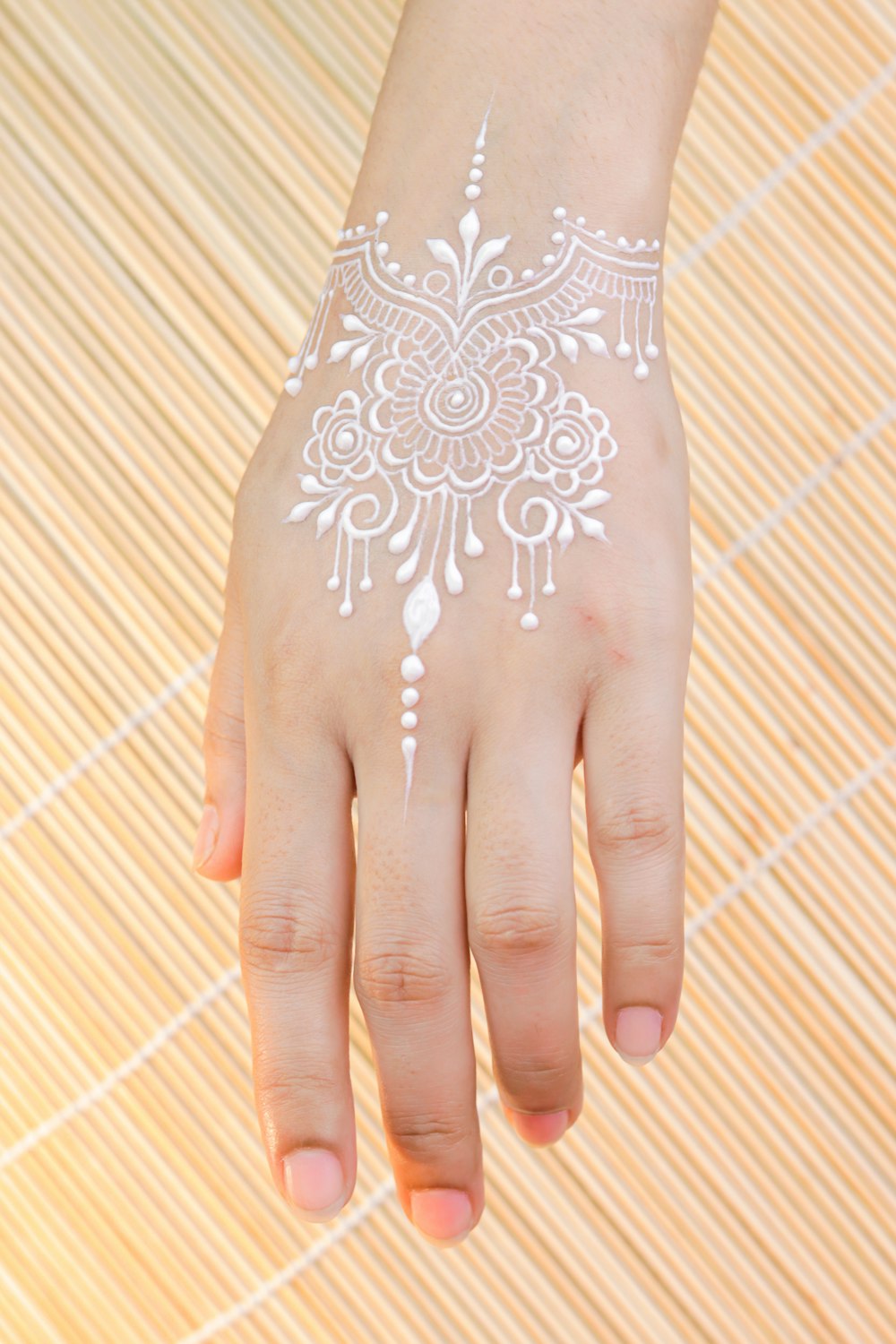 person with white and red floral hand tattoo