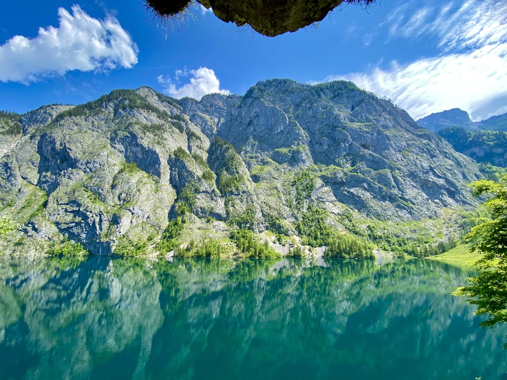 green and white mountain beside body of water during daytime