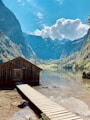 brown wooden house near lake and mountains during daytime