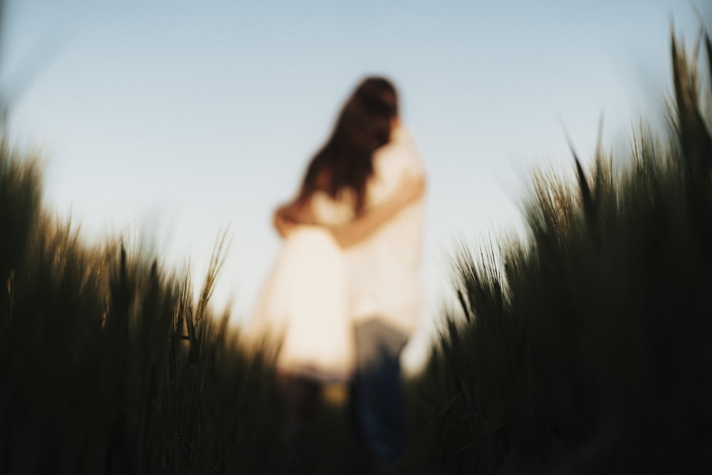 donna in camicia bianca a maniche lunghe in piedi sul campo di erba verde durante il giorno