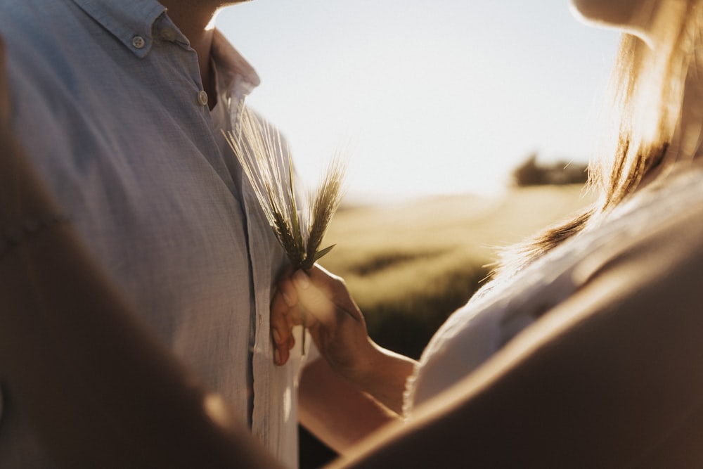 person in white button up shirt holding brown plant during daytime