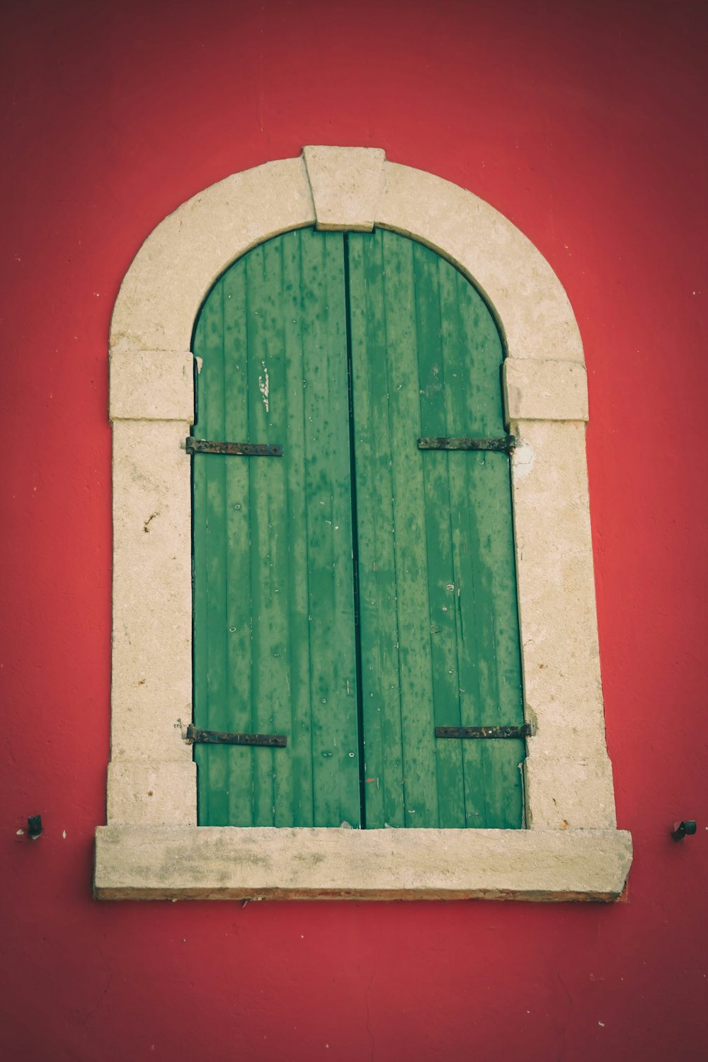 green wooden window on red wall
