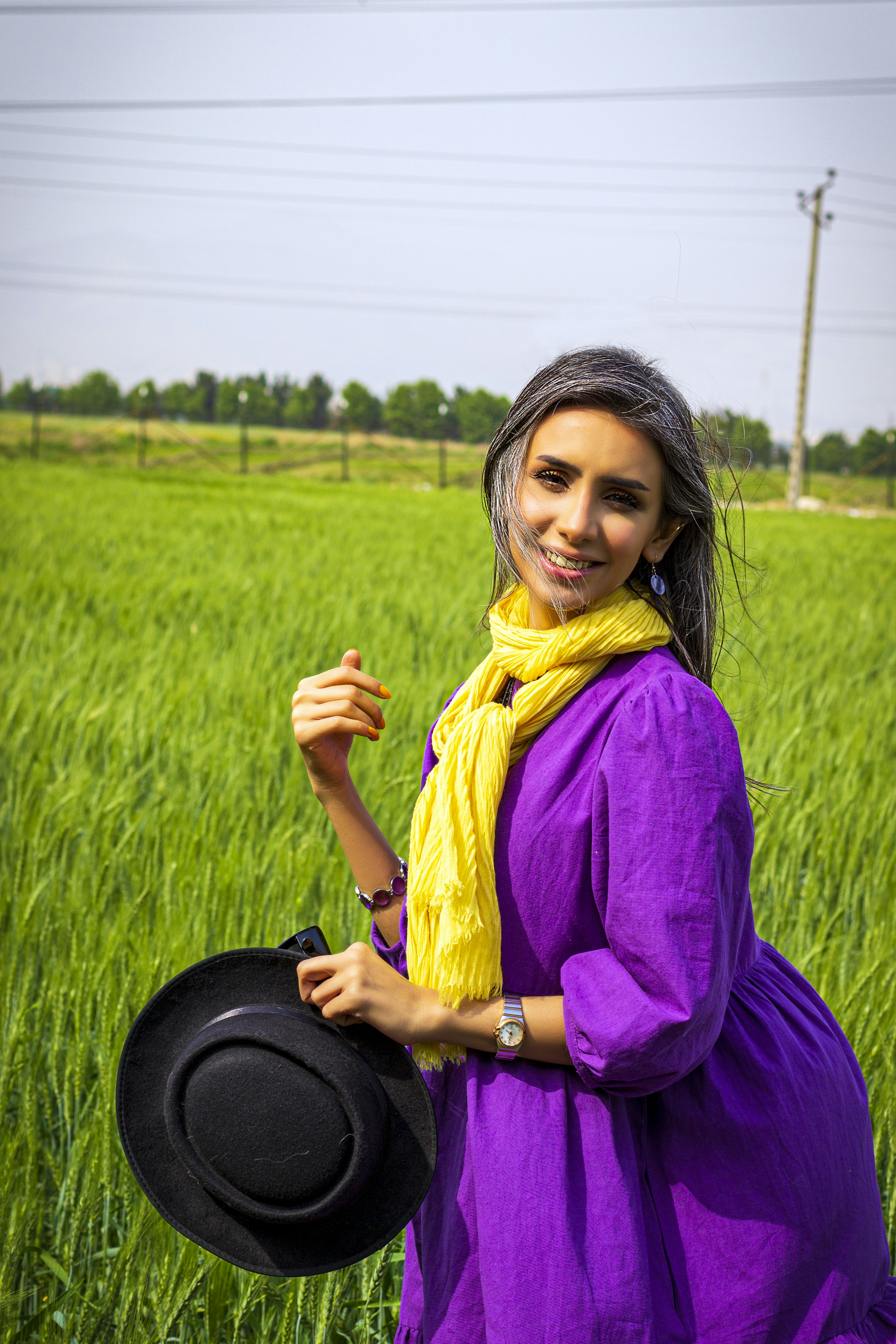 woman in purple long sleeve shirt and yellow scarf sitting on green grass field during daytime
