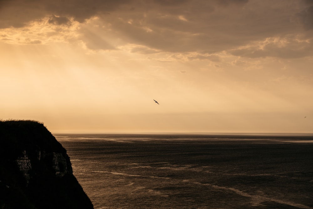 silhouette of person standing on hill during sunset