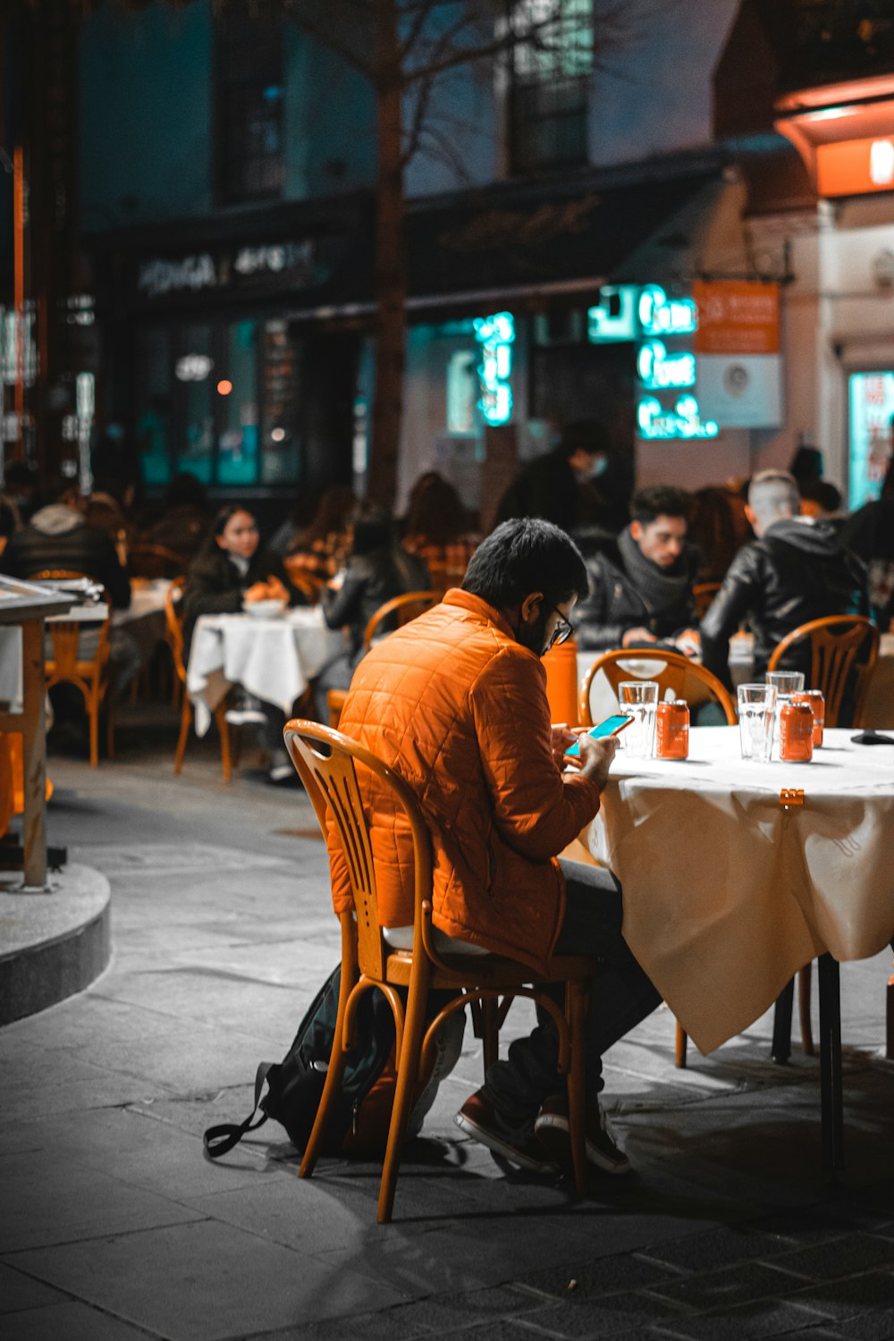 man in orange hoodie sitting on brown wooden chair