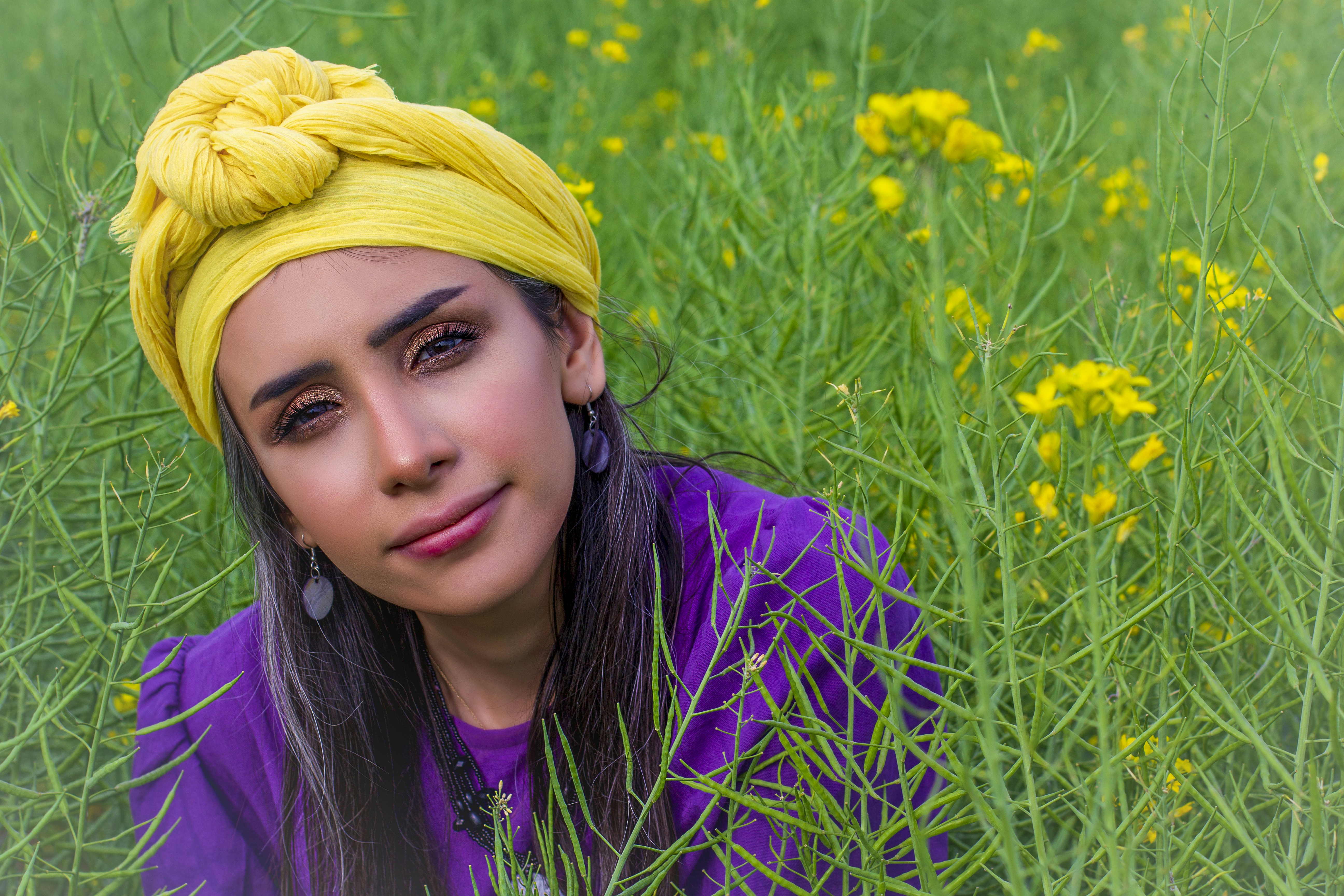 woman in purple shirt and yellow head band on yellow flower field during daytime