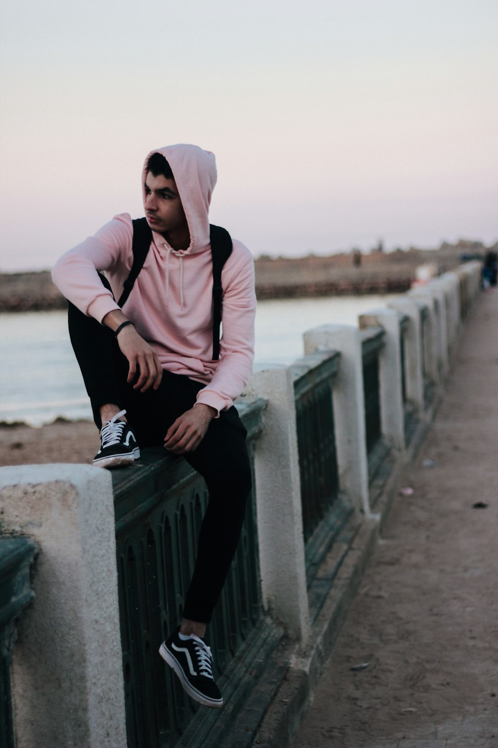 man in brown hoodie sitting on concrete bench