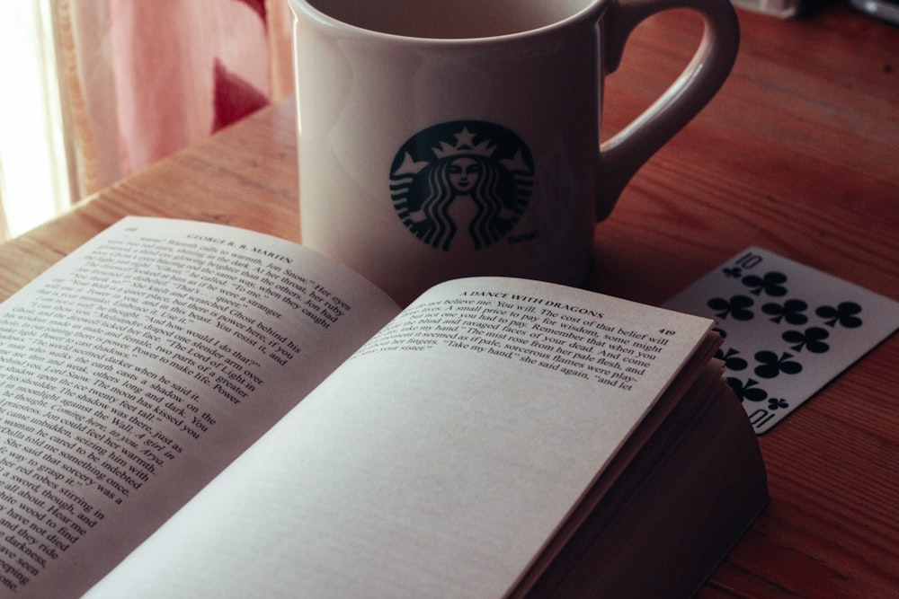 white and green starbucks ceramic mug on white book page