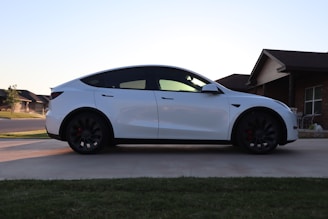 A clean car parked in front of a modern house.