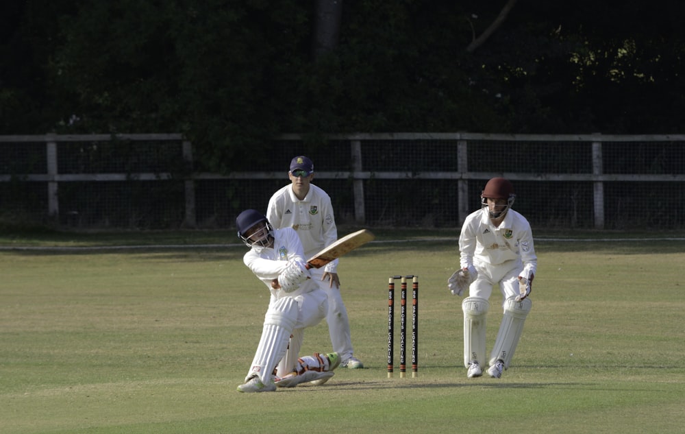 2 men playing cricket on green grass field during daytime