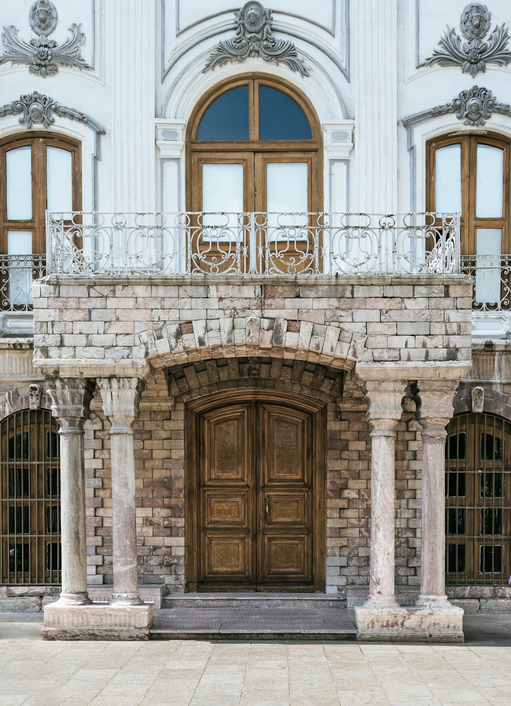 白いコンクリートの建物に茶色の木製のドア