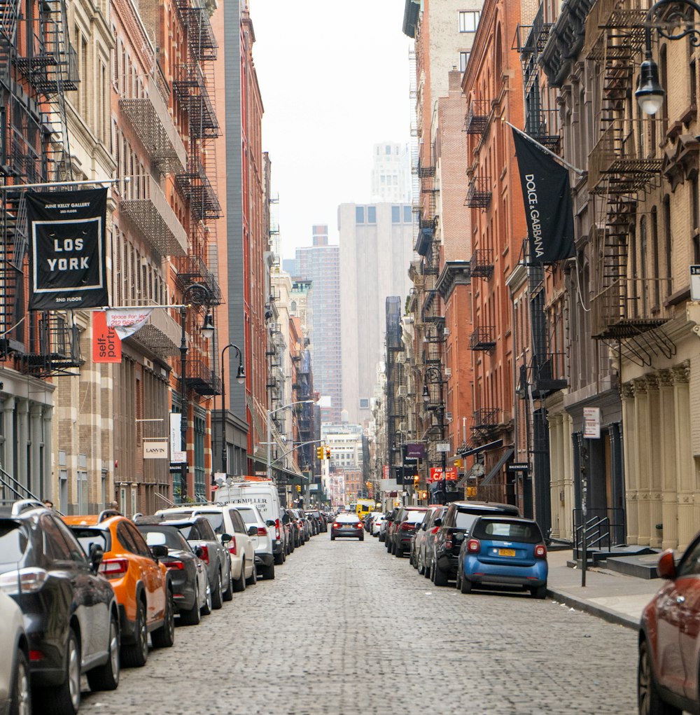 cars parked on sidewalk in between buildings during daytime