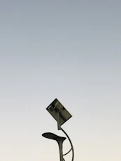 A sleek solar street light illuminating a quiet urban street at dusk.