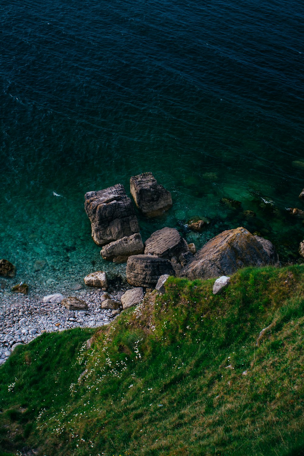 rocky mountain beside body of water during daytime