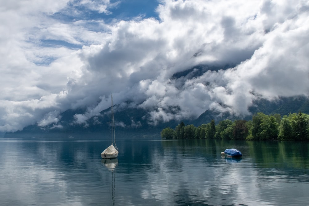 white and blue boat on lake under white clouds during daytime
